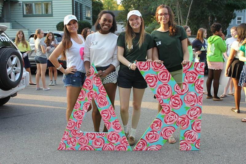 Members of Kappa Delta holding their letters while preparing for a homecoming parade.